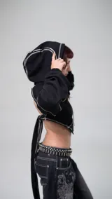 Buzo negro corto con capucha y espalda descubierta, con tiras para atar en la espalda y detalles de costuras blancas.