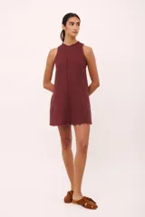 Vestido corto color borgoña de lino italiano, con cuello redondo y corte musculosa. Presenta detalle desflecado en cuello y ruedo.