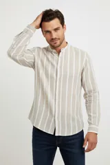 Camisa de algodón a rayas verticales color beige y blanco, de corte holgado, con cuello mao y cierre frontal con botones.