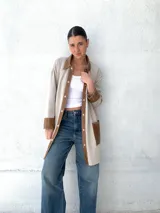 Camisa color beige con detalles en cuero color marrón en cuello, solapa, cierre y puños. Corte recto y abotonada al frente.