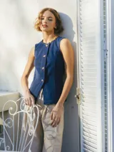 Chaleco de denim azul con escote en V, botones dorados y ribete de cuentas en el cuello.