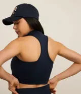 Top deportivo negro con cuello alto, escote halterneck y media cremallera. Confeccionado en poliamida seamless sin copa.