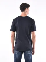 Remera negra de corte oversized con bolsillo en el pecho y detalle de bloque gris en el lateral.