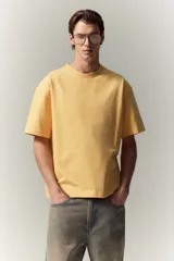 Remera de algodón color amarillo, de corte holgado, con cuello redondo ribeteado, hombros caídos y bajo recto.