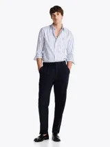 Camisa de popelín de puro algodón a rayas verticales blancas y celestes con logo de Tommy Hilfiger bordado en el pecho. Cuenta con cuello abotonado, mangas largas con puños abotonados y corte regular.