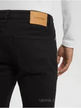 Pantalón de jean negro, corte slim fit, con cierre de botón y cremallera, diseño de cinco bolsillos, herrajes metálicos con logo y parche en la cintura trasera.