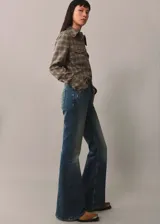 Pantalón de jean acampanado de tiro alto, color azul denim, con cinco bolsillos y trabillas.