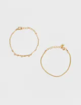 Set de dos pulseras doradas. Una es una cadena fina y la otra es una cadena con eslabones tubulares.