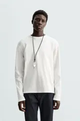 Camiseta blanca de manga larga con cuello redondo y textura cuadriculada.