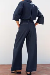 Pantalón de jean azul oscuro, corte wide leg, tiro alto con pinzas delanteras, bolsillos laterales y cierre frontal con cremallera y botón.