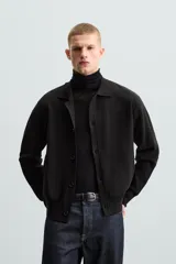 Cárdigan negro de punto con cuello solapa, manga larga y cierre frontal con botones.