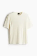Remera color crema de punto acanalado suave de mezcla de algodón y viscosa. Tiene cuello redondo y mangas cortas con ribete acanalado fino en cuello, puños y bajo.