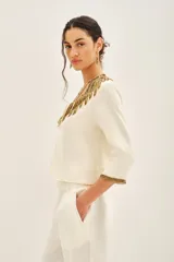 Saco corto color crema con escote en V y mangas 3/4. Confeccionado en viscosa crepe con bordado de mostacillas, canutillos y lentejuelas doradas.