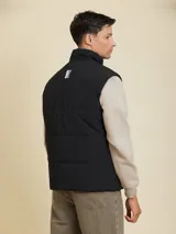 Chaleco negro, acolchado, con cierre frontal y múltiples bolsillos.