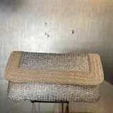 Bolso de mano tipo sobre, tejido en color plateado con reborde bordado en beige. Incluye asa de cadena para llevar al hombro.