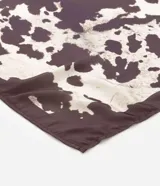 Pañuelo rectangular de satén con estampado animal print de vaca y acabado satinado. 