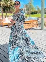 Vestido largo de polysilk con estampado paisley en tonos azul, celeste y dorado. Tiene escote en V, mangas largas acampanadas y corte amplio.