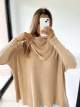 Sweater color beige de tejido de punto acanalado, con cuello alto caído y mangas largas.