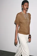 Top marrón de tejido crochet con cuello barco y manga corta.