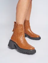 Bota corta de cuero color marrón, con cierre lateral, suela de goma negra y taco cuadrado.