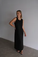 Vestido largo azul marino de tejido acanalado, con escote redondo y mangas cortas tipo hombrera. Presenta una abertura lateral en la falda.