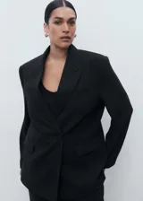 Blazer negro de corte recto, con cuello de pico cruzado y cierre de un solo botón. Presenta solapas con muesca, bolsillo de ribete en el pecho y dos bolsillos de solapa laterales.
