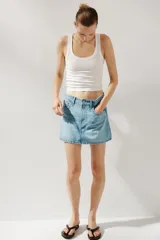 Minifalda de jean celeste con tiro medio, trabillas, cinco bolsillos y cierre frontal con cremallera y botón metálico.