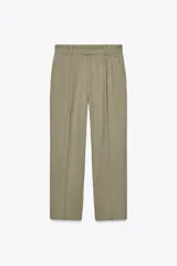Pantalón color verde oliva de tiro medio con cintura con trabillas, bolsillos laterales, pinzas delanteras y raya planchada. Cierre frontal con cremallera, botón y ganchos metálicos.