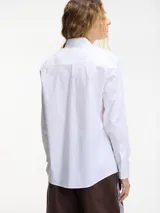 Camisa blanca de algodón con botones frontales y cuello camisero con apliques de pedrería.
