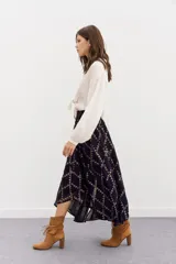 Falda larga de viscosa jacquard con lurex dorado, estampado geométrico, tajo central, ruedo irregular y cintura elastizada.
