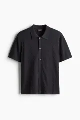 Camisa de manga corta en tejido de punto texturizado de mezcla de algodón. Modelo con cuello clásico, abotonadura frontal y bajo recto. Corte estándar.