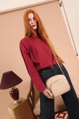 Bandolera de cuero sintético color beige, con diseño compacto y elegante. Cuenta con un bolsillo frontal con cierre y un compartimento principal con cierre. La correa es regulable.