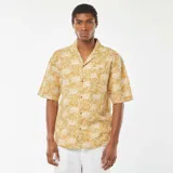 Camisa de manga corta color mostaza con estampado de palmeras en blanco.