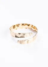 Brazalete dorado abierto, con textura martillada y diseño entrelazado.