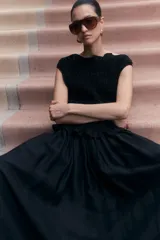 Top negro sin mangas de viscosa con diseño smock, escote barco con volados y peplum.
