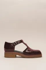 Zapato guillermina de cuero vacuno charol color negro, con suela de goma color marrón.