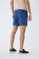Short de baño celeste con estampado de líneas curvas en azul. Cuenta con cintura elástica con cordón ajustable, dos bolsillos laterales, un bolsillo trasero, suspensor interno y logo bordado.