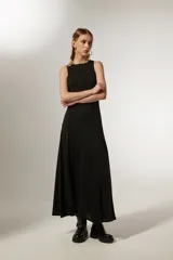 Vestido negro sin mangas de poliéster, corte al cuerpo, largo midi con abertura lateral y cuello redondo.