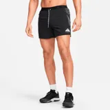 Short deportivo negro con logo Nike Trail estampado en blanco, cintura elástica con cordón ajustable y paneles laterales en gris.