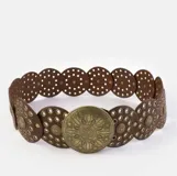 Cinturón negro con apliques circulares plateados y hebilla circular plateada con diseño labrado.