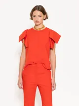 Top color naranja con cuello redondo y mangas cortas con volados.
