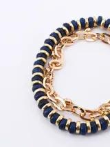 Set de tres pulseras elásticas: una de cuentas facetadas azul marino con detalles dorados, una de cuentas pequeñas blancas y doradas, y una de cadena dorada con eslabones ovalados.
