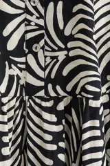 Vestido midi con estampado de hojas en blanco y negro, cuello mao, escote en V con botones, mangas globo tres cuartos con puños finos y falda acampanada con fruncido escalonado.