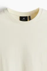 Remera de punto liviano color crema, con cuello redondo ribeteado y bajo recto. Corte estándar. Confeccionada con tejido funcional COOLMAX®, una fibra exclusiva de poliéster de secado rápido que elimina la humedad y regula la temperatura corporal.