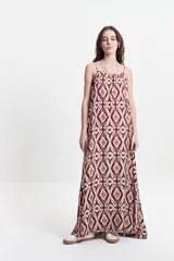 Vestido largo negro con estampado abstracto, de silueta amplia, con breteles finos y escote redondeado. Tiene un frunce sutil en el escote delantero y trasero que genera una caída fluida y relajada.