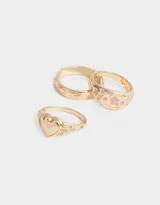 Set de tres anillos dorados con diferentes diseños: uno con forma de corazón, otro con flores rosas y otro con diseño de soles.