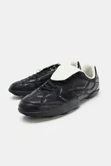 Zapato deportivo estilo running color negro con detalle de acolchado en el cuerpo, suela con relieve, cierre mediante cordones y lengüeta.