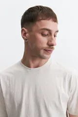 Remera de manga corta color crema con estampado abstracto en blanco, de corte recto y cuello redondo.