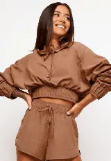 Chaqueta cropped negra con manga larga, elástico en los puños y cordón ajustable en el cuello, diseñada para un estilo relajado.