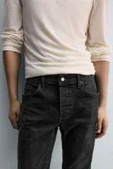 Pantalón de jean azul oscuro con efecto lavado y roturas en las rodillas, de corte ajustado al cuerpo desde la cintura hasta el tobillo.